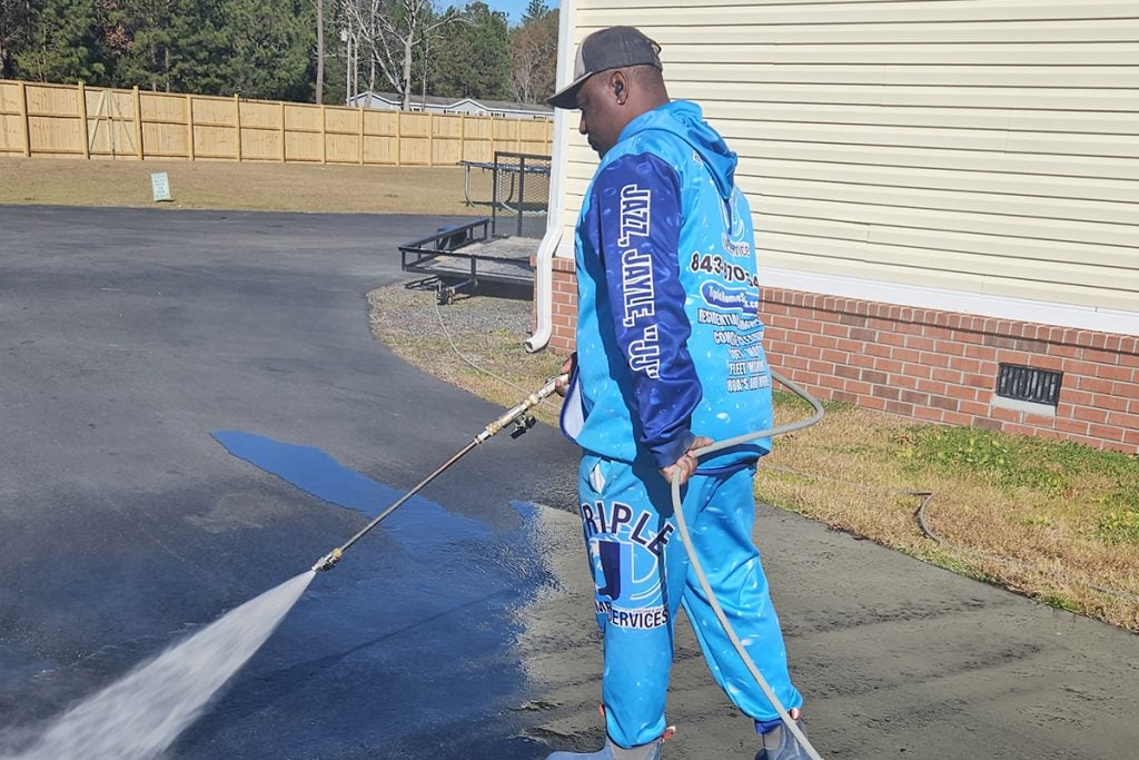 Justin Eady of Triple J pressure washing a driveway in North Charleston